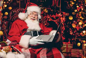 A portrait of Santa Claus sitting at his home with a laptop. Miracle time. Christmas, New Year.